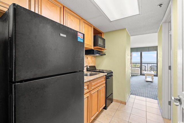 2401 S Ocean Blvd S Unit 267, Myrtle Beach, SC 29577 - kitchen featuring black appliances, light tile patterned flooring, brown cabinetry, baseboards, and under cabinet range hood