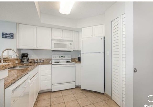 kitchen featuring light stone countertops, a sink, light tile patterned floors, white appliances, and white cabinetry