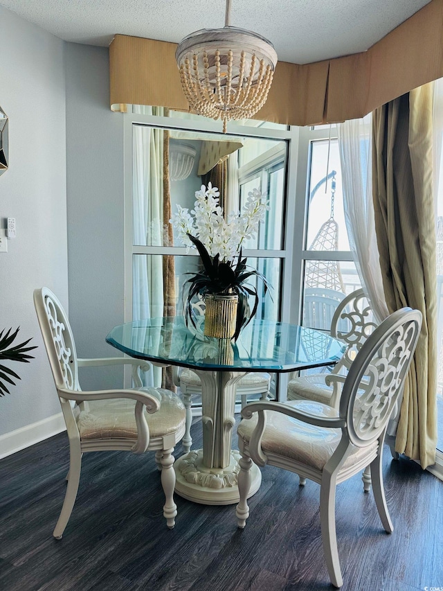 dining space featuring baseboards, a textured ceiling, wood finished floors, and a notable chandelier