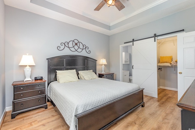 6253 Catalina Dr Unit 131, North Myrtle Beach, SC 29582 - bedroom featuring a barn door, light wood-style floors, a tray ceiling, crown molding, and a spacious closet