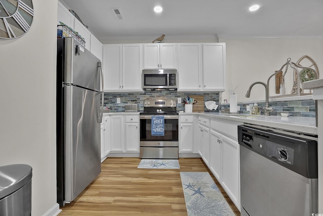 601 Hillside Dr N Unit 1405, North Myrtle Beach, SC 29582 - kitchen featuring white cabinets, light wood-style flooring, stainless steel appliances, tasteful backsplash, and ornamental molding