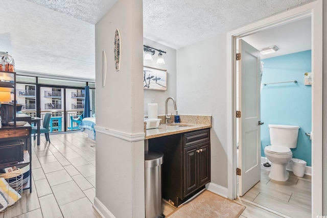 bathroom featuring a textured ceiling, toilet, vanity, and baseboards
