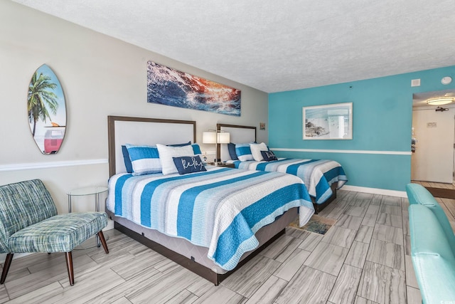 bedroom featuring a textured ceiling, wood finish floors, and baseboards