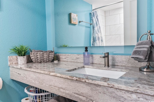 bathroom featuring a textured wall, vanity, and a shower with curtain