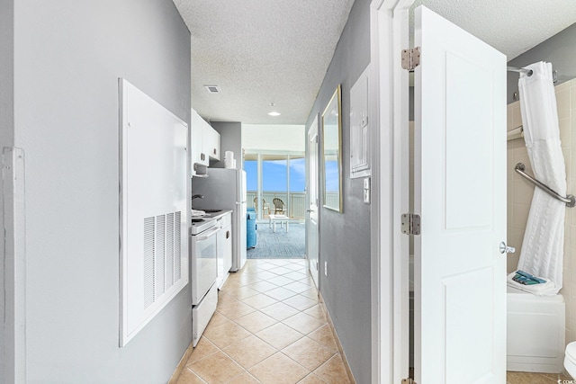 hall with a textured ceiling and light tile patterned floors