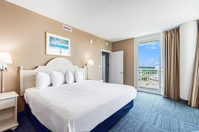 bedroom featuring access to exterior, dark colored carpet, and a textured ceiling