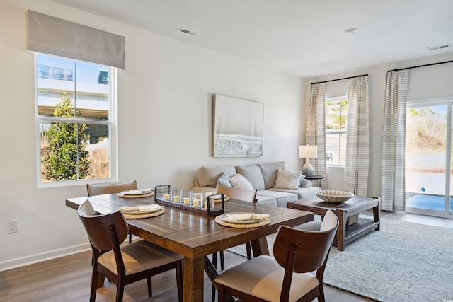 dining space with visible vents, baseboards, and wood finished floors