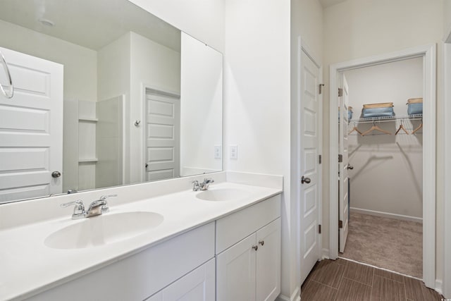 full bath with double vanity, a sink, and a walk in closet