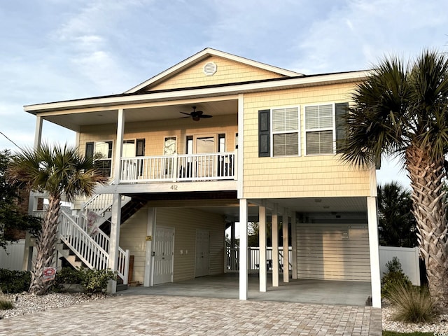 raised beach house featuring a porch, stairway, ceiling fan, a carport, and decorative driveway