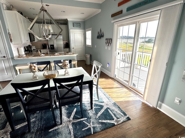 dining area with an inviting chandelier, ornamental molding, baseboards, and light wood-style flooring