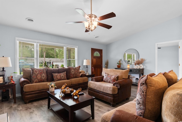 living area with visible vents, light wood-style floors, ceiling fan, and lofted ceiling