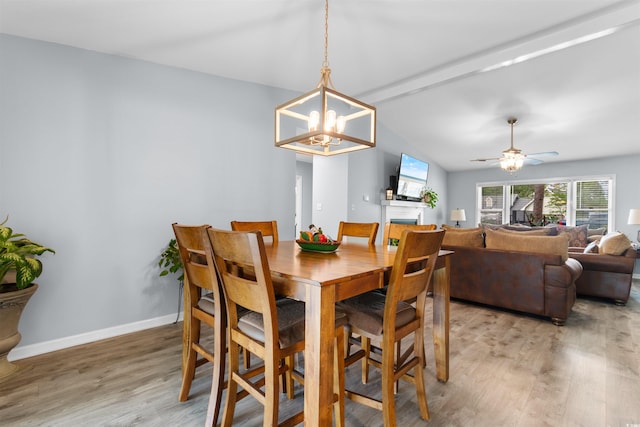 dining space featuring baseboards, lofted ceiling with beams, light wood-style flooring, and ceiling fan with notable chandelier