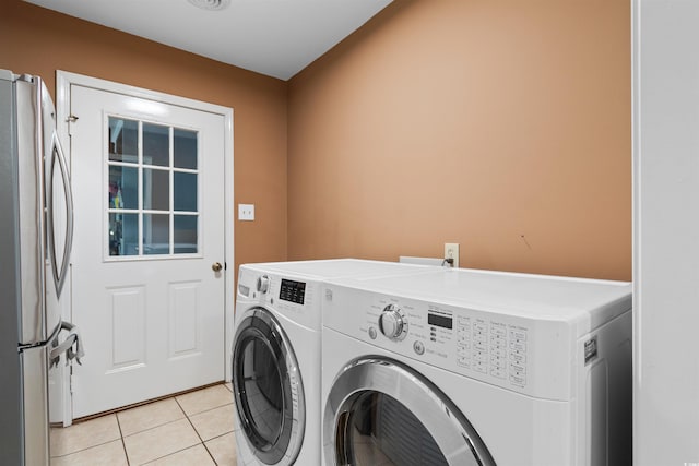 clothes washing area featuring laundry area, light tile patterned flooring, and washing machine and clothes dryer