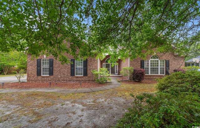 view of property hidden behind natural elements with brick siding