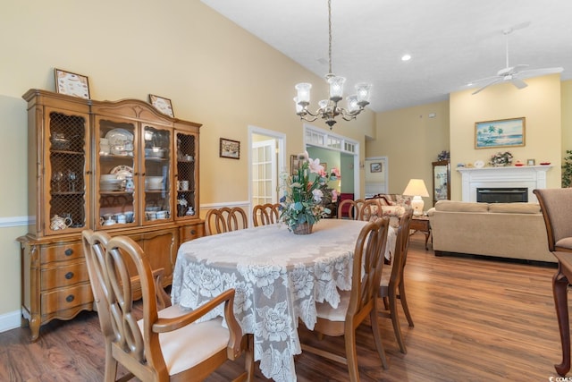 dining space with a fireplace, ceiling fan with notable chandelier, recessed lighting, and wood finished floors