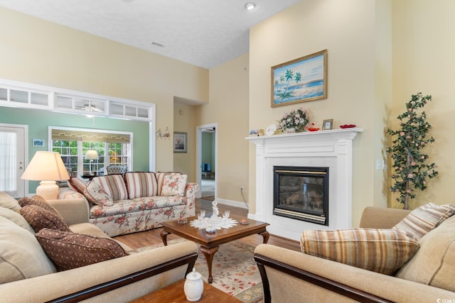 living area featuring baseboards, a glass covered fireplace, wood finished floors, and visible vents