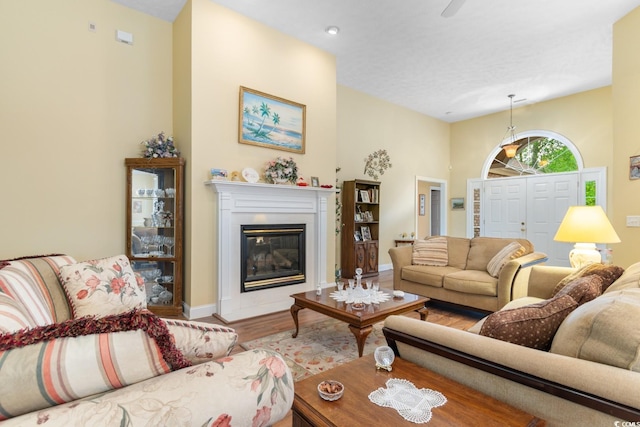 living area with baseboards, a glass covered fireplace, and wood finished floors