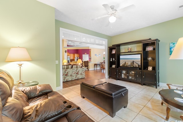 living room with light tile patterned floors, ceiling fan, and baseboards