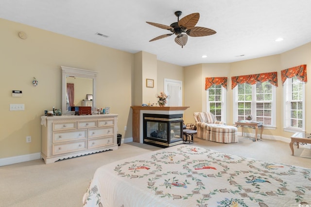 bedroom with visible vents, a multi sided fireplace, baseboards, and light colored carpet