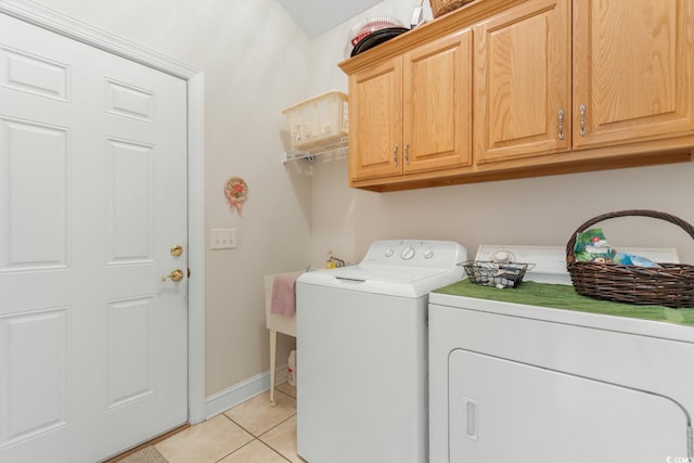 laundry room featuring washing machine and clothes dryer, baseboards, light tile patterned floors, and cabinet space