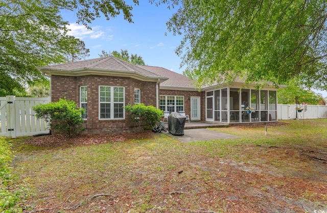 back of property with a sunroom, a fenced backyard, brick siding, and a patio