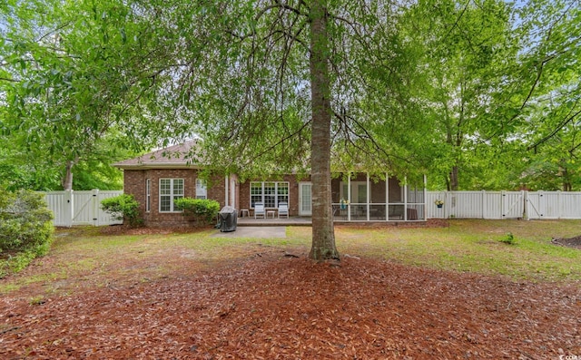 exterior space featuring a patio, a fenced backyard, a sunroom, a gate, and brick siding