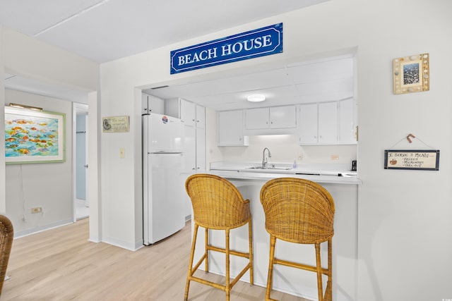 311 71st Ave N Unit 3-D, Myrtle Beach, SC 29572 - kitchen featuring freestanding refrigerator, a peninsula, light wood-style floors, light countertops, and white cabinetry