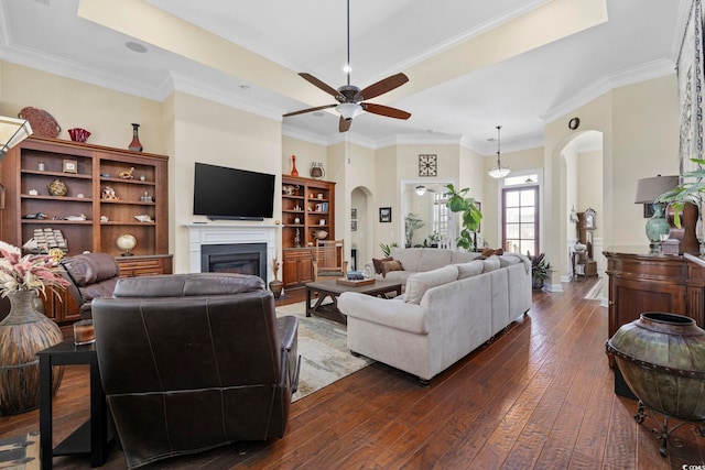 200 Stonefly Ct, Murrells Inlet, SC 29576 - living room featuring dark wood-style flooring, a glass covered fireplace, ceiling fan, a tray ceiling, and arched walkways