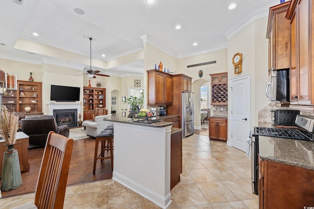 200 Stonefly Ct, Murrells Inlet, SC 29576 - kitchen with a peninsula, a fireplace, ceiling fan, arched walkways, and stainless steel appliances
