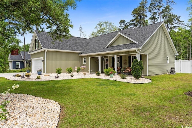 craftsman-style home with a front lawn, covered porch, roof with shingles, an attached garage, and fence