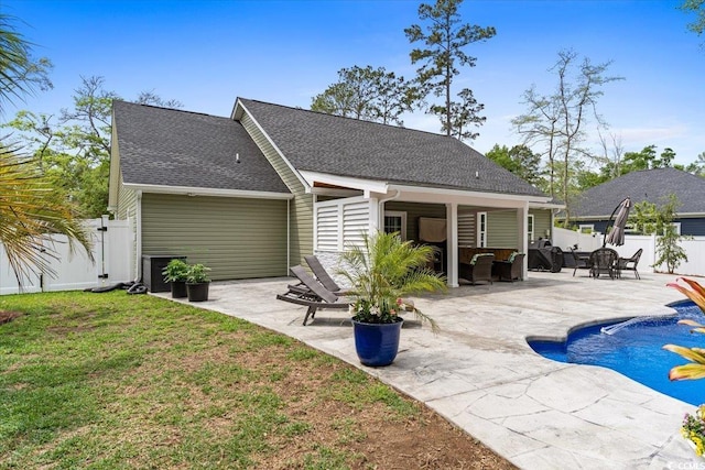 back of house featuring a fenced backyard, a gate, a fenced in pool, a patio, and a lawn
