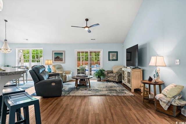 living area with lofted ceiling, a wealth of natural light, wood finished floors, and ceiling fan