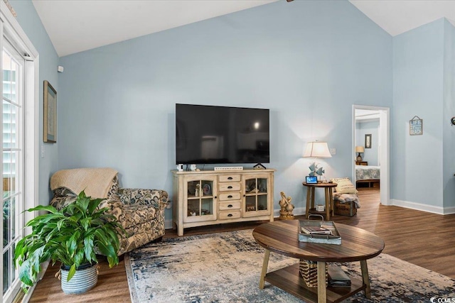 living area featuring wood finished floors, high vaulted ceiling, and baseboards