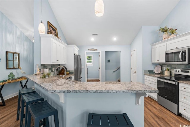 kitchen with a sink, white cabinets, stainless steel appliances, and tasteful backsplash