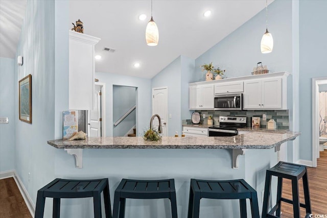 kitchen with dark wood-style floors, visible vents, vaulted ceiling, white cabinets, and appliances with stainless steel finishes