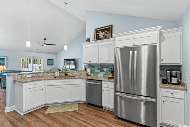 kitchen featuring lofted ceiling, stainless steel appliances, a peninsula, and a sink