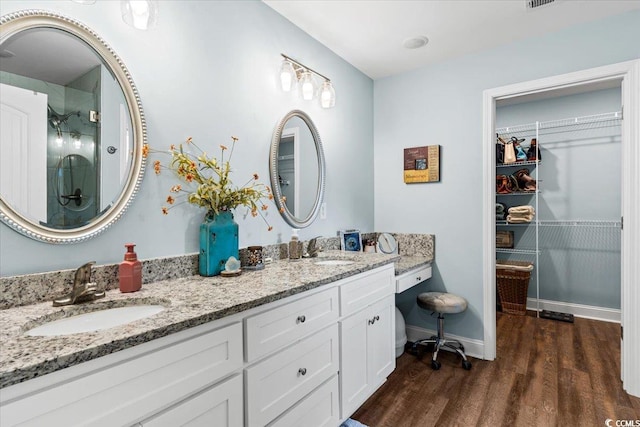 full bath with double vanity, wood finished floors, an enclosed shower, and a sink