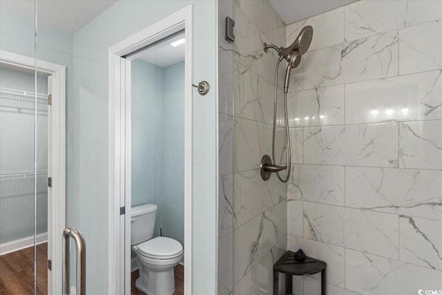 bathroom with toilet, a stall shower, and wood finished floors