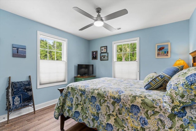 bedroom with visible vents, multiple windows, wood finished floors, and baseboards