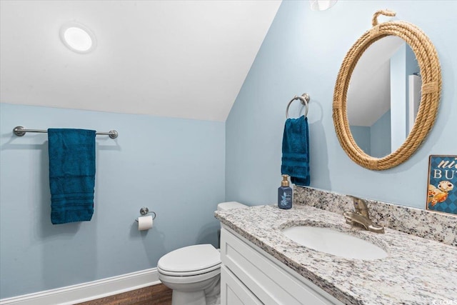 bathroom featuring vanity, wood finished floors, toilet, baseboards, and lofted ceiling