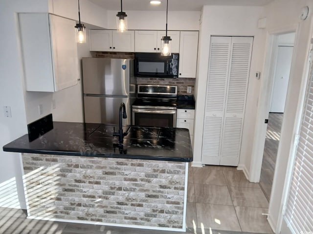 kitchen with appliances with stainless steel finishes, a peninsula, white cabinetry, decorative backsplash, and pendant lighting