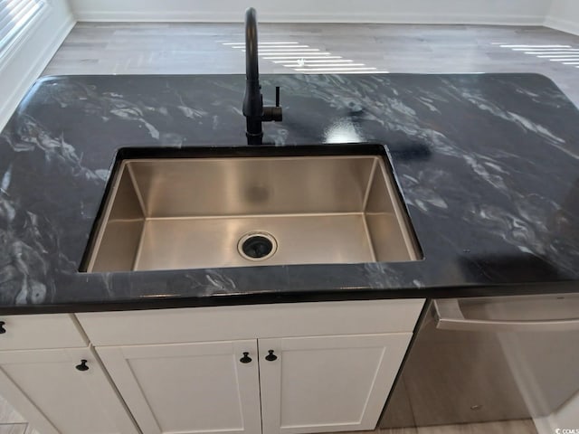 room details with stainless steel dishwasher, white cabinetry, and a sink