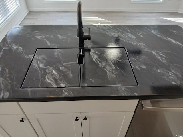 details with white cabinets, dark countertops, and a sink