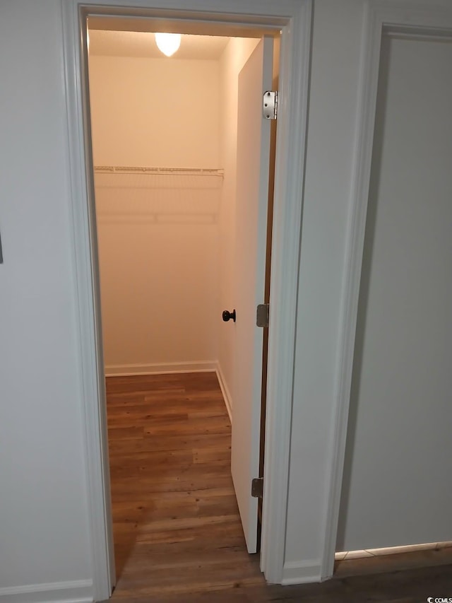 corridor with baseboards and wood finished floors