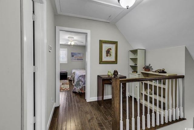 hallway featuring attic access, baseboards, dark wood-style flooring, and lofted ceiling