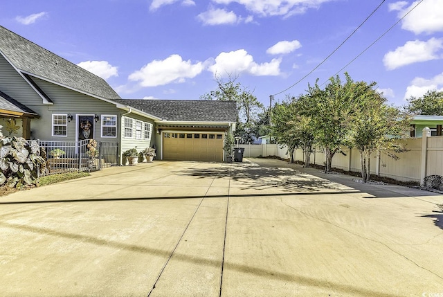 view of side of home featuring fence, a garage, and driveway