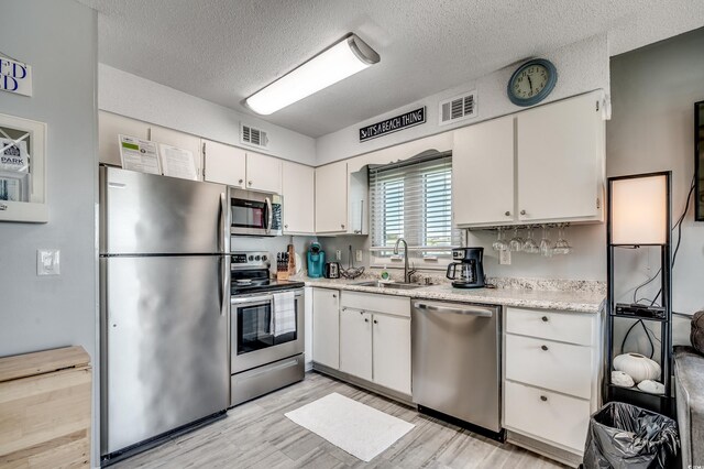 1208 S Ocean Blvd Unit H, North Myrtle Beach, SC 29582 - kitchen featuring stainless steel appliances, a sink, white cabinetry, light countertops, and a textured ceiling