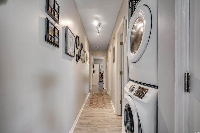 1208 S Ocean Blvd Unit H, North Myrtle Beach, SC 29582 - clothes washing area featuring stacked washer / dryer, light wood-type flooring, baseboards, and rail lighting