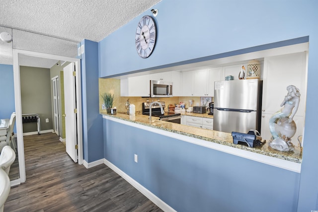 9820 Queensway Blvd Unit 704, Myrtle Beach, SC 29572 - kitchen with stainless steel appliances, light stone counters, dark wood finished floors, white cabinetry, and a textured ceiling