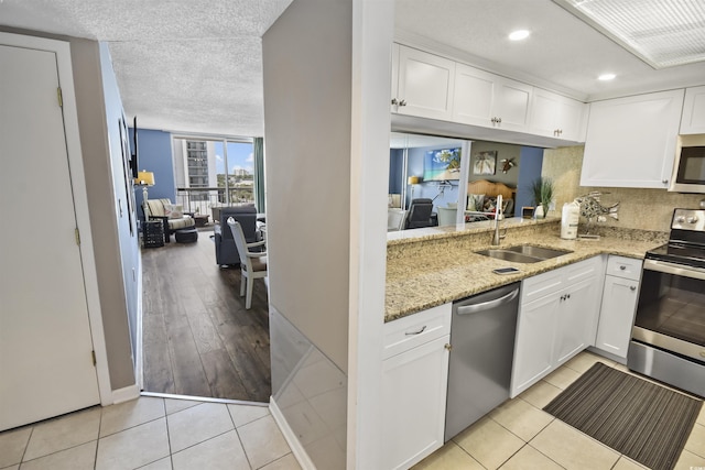 9820 Queensway Blvd Unit 704, Myrtle Beach, SC 29572 - kitchen with stainless steel appliances, light stone counters, white cabinetry, light tile patterned floors, and backsplash